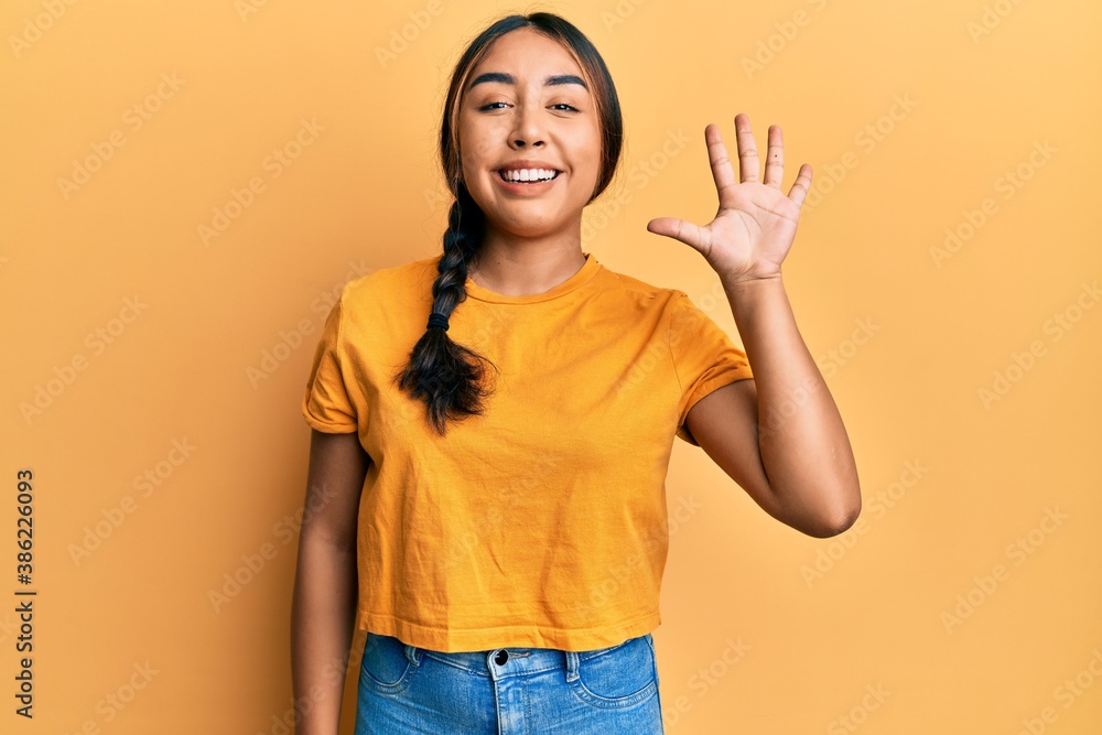 Young latin woman wearing casual clothes showing and pointing up with fingers number five while smiling confident and happy. Young latin woman wearing casual clothes showing and pointing up with fingers number five while smiling confident and happy.