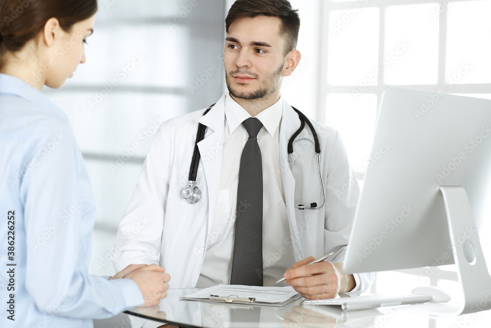 Doctor and patient. Physician man filling up medication history records form while sitting at the glass desk in medical office or clinic. Medicine and healthcare concept Doctor and patient. Physician man filling up medication history records form while sitting at the glass desk in medical office or clinic. Medicine and healthcare concept