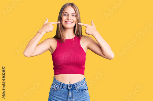 Young beautiful blonde woman wearing elegant summer shirt smiling cheerful showing and pointing with fingers teeth and mouth. dental health concept.