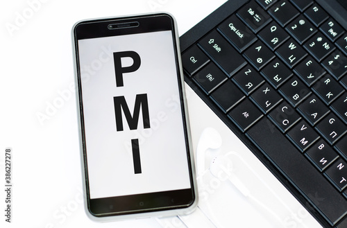 Text PMI on the phone screen against the background of the laptop keyboard photo