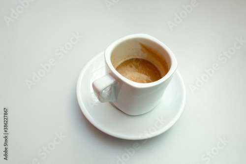Isolated shot of a half full cup of coffee with milk on white background © Leoniek