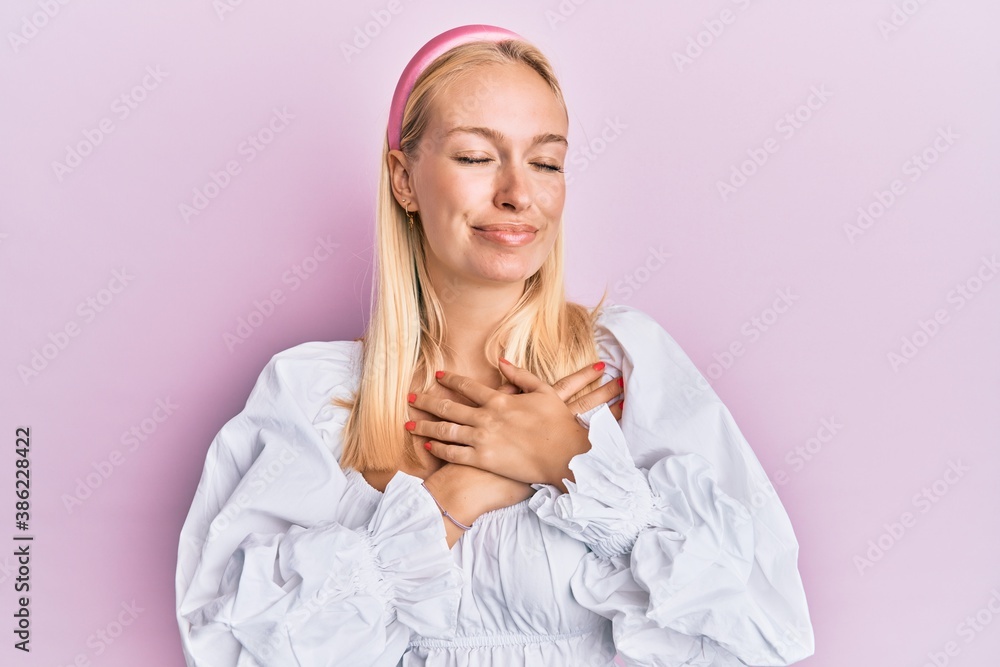 Young blonde girl wearing casual clothes smiling with hands on chest, eyes closed with grateful gesture on face. health concept. Young blonde girl wearing casual clothes smiling with hands on chest, eyes closed with grateful gesture on face. health concept.