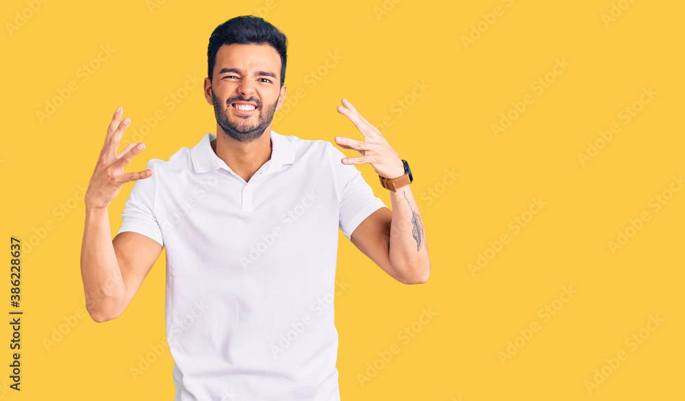 Young handsome hispanic man wearing casual clothes shouting frustrated with rage, hands trying to strangle, yelling mad Young handsome hispanic man wearing casual clothes shouting frustrated with rage, hands trying to strangle, yelling mad