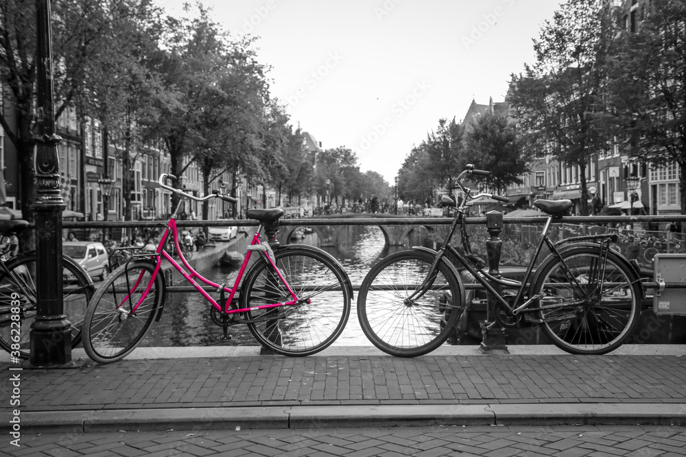 A picture of a pink bike on the bridge over the channel in Amsterdam. The background is black and white. A picture of a pink bike on the bridge over the channel in Amsterdam. The background is black and white.