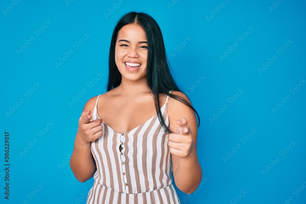 Young beautiful asian girl wearing casual clothes pointing fingers to camera with happy and funny face. good energy and vibes. Young beautiful asian girl wearing casual clothes pointing fingers to camera with happy and funny face. good energy and vibes.