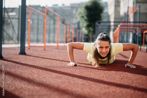 Attractive fit woman doing push up from ground at stadium