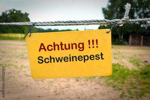 Bild auf Leinwand Schild mit der Aufschrift Achtung Schweinepest an einem Zaun zu einem Bauernho