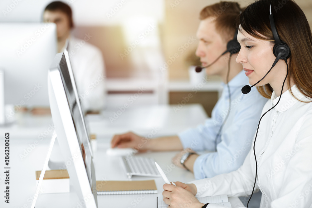 Asian woman working at customer service office. Business concept. Group of diverse operators at work in sunny call center. Asian woman working at customer service office. Business concept. Group of diverse operators at work in sunny call center.