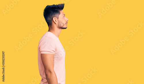 Handsome latin american young man wearing casual clothes looking to side, relax profile pose with natural face with confident smile.