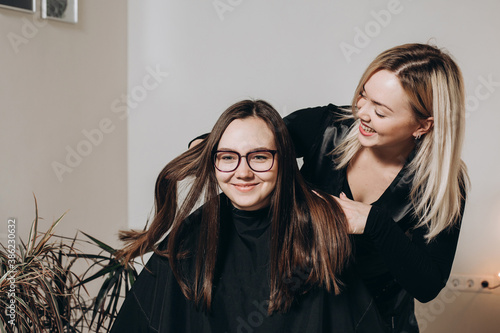 A female hairdresser of European appearance works with the hair of a model. Home beauty salon. Barbershop. Healthy strong hair.
