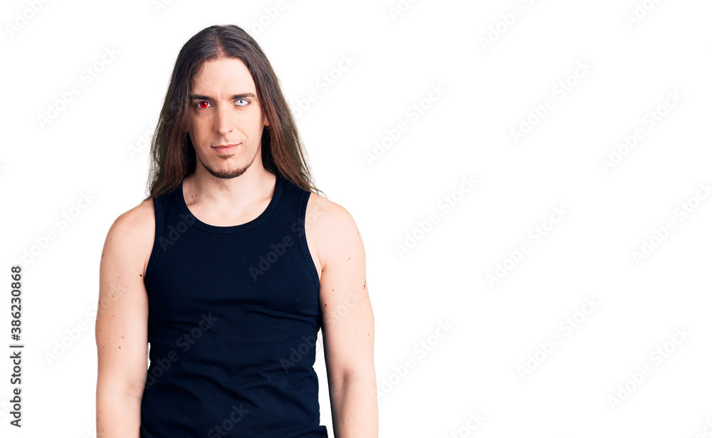 Young adult man with long hair wearing rocker style with black clothes and contact lenses with serious expression on face. simple and natural looking at the camera. Young adult man with long hair wearing rocker style with black clothes and contact lenses with serious expression on face. simple and natural looking at the camera.