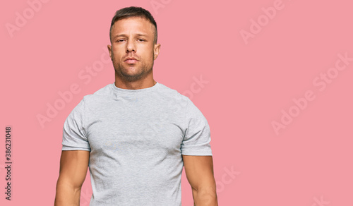Handsome muscle man wearing casual grey tshirt with serious expression on face. simple and natural looking at the camera.