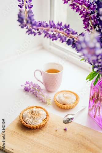 selective focus. still life of green tea in a beautiful mug with cakes tart. nice breakfast. table setting with fresh flowers.