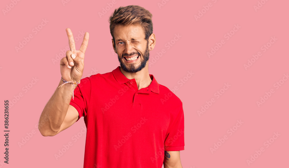 Handsome blond man with beard wearing casual clothes smiling with happy face winking at the camera doing victory sign. number two. Handsome blond man with beard wearing casual clothes smiling with happy face winking at the camera doing victory sign. number two.