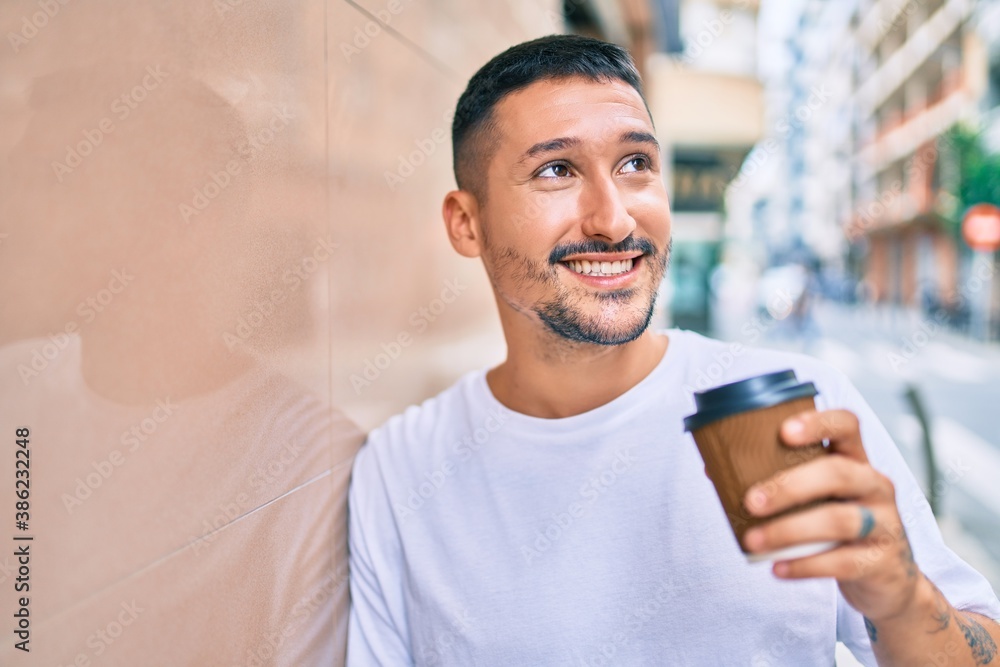 Young hispanic man drinking take away coffee leaning on the wall at street of city. Young hispanic man drinking take away coffee leaning on the wall at street of city.