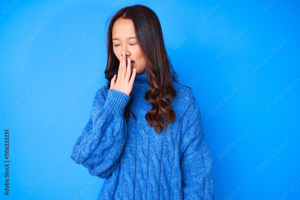 Young beautiful chinese girl wearing casual winter sweater bored yawning tired covering mouth with hand. restless and sleepiness. Young beautiful chinese girl wearing casual winter sweater bored yawning tired covering mouth with hand. restless and sleepiness.