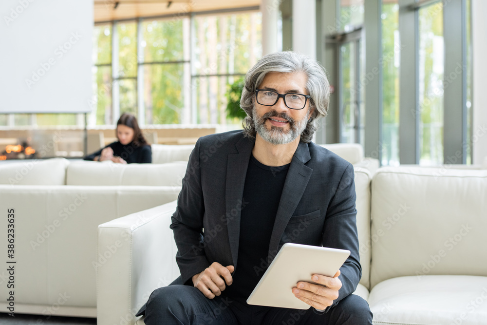Successful mature businessman sitting on soft leather couch in front of camera Successful mature businessman sitting on soft leather couch in front of camera
