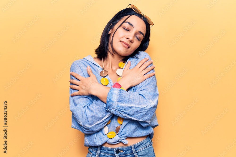 Young beautiful latin woman wearing casual clothes hugging oneself happy and positive, smiling confident. self love and self care Young beautiful latin woman wearing casual clothes hugging oneself happy and positive, smiling confident. self love and self care