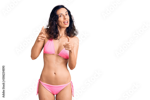 Young beautiful hispanic woman wearing bikini pointing fingers to camera with happy and funny face. good energy and vibes. © Krakenimages.com