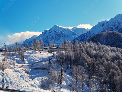 View of a ski resort with snow-capped mountain peaks, forest and slopes
