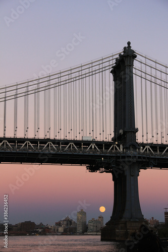 Moonrise low under bridge at sunset manhattan