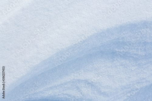 Beautiful winter background with snowy ground. Natural snow texture. Wind sculpted patterns on snow surface. Closeup top view with copy space. © Andrei Stepanov