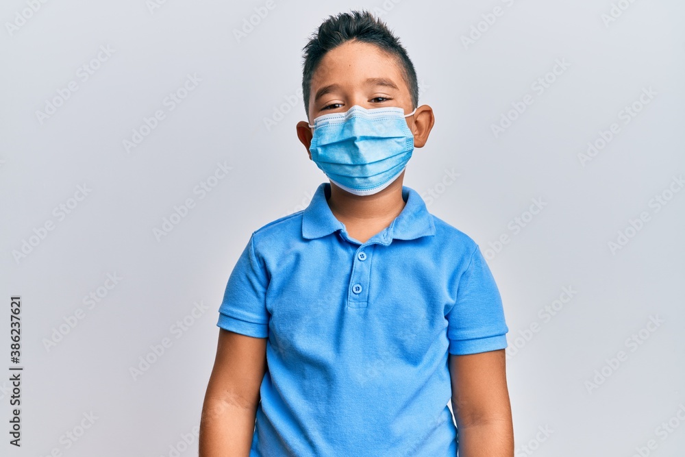 Little boy hispanic kid wearing medical mask with a happy and cool smile on face. lucky person. Little boy hispanic kid wearing medical mask with a happy and cool smile on face. lucky person.
