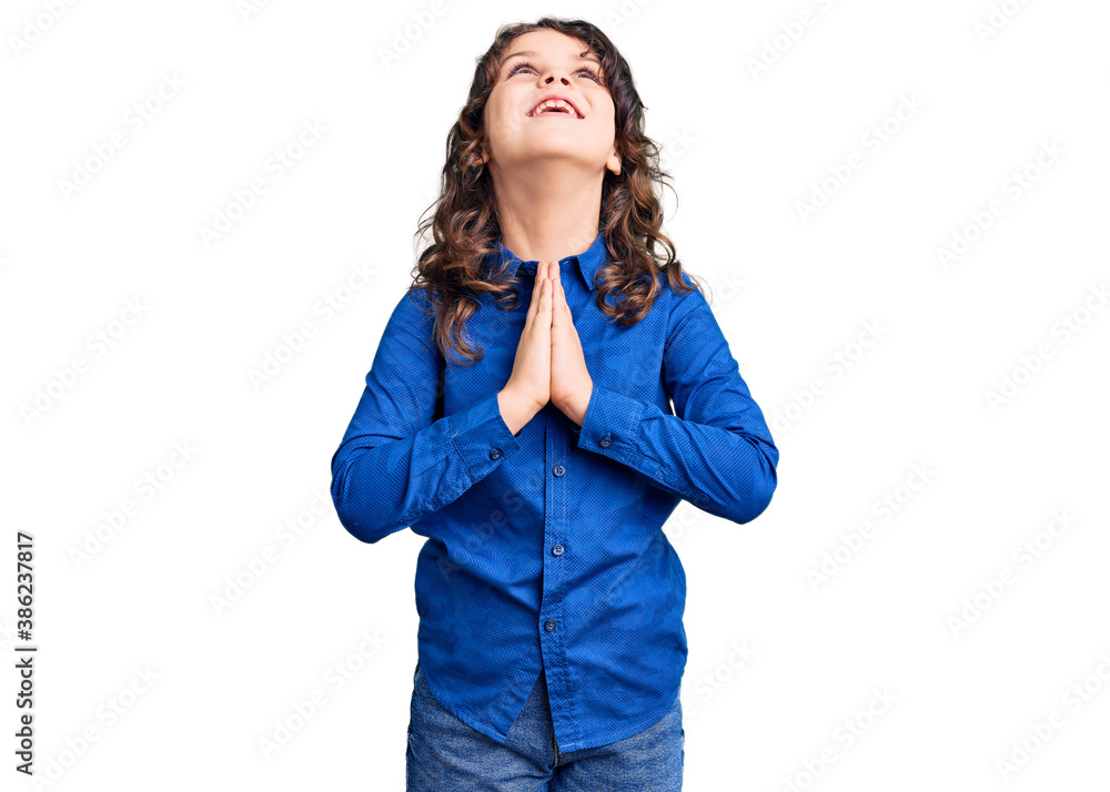 Cute child with long hair wearing casual clothes begging and praying with hands together with hope expression on face very emotional and worried. begging. Cute child with long hair wearing casual clothes begging and praying with hands together with hope expression on face very emotional and worried. begging.