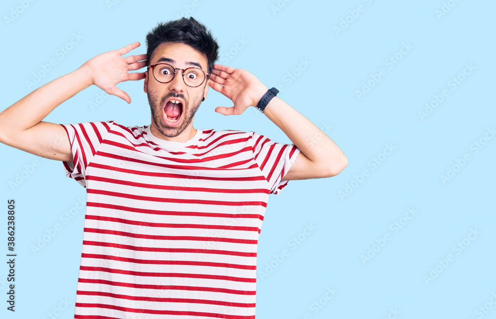 Young hispanic man wearing casual clothes crazy and scared with hands on head, afraid and surprised of shock with open mouth Young hispanic man wearing casual clothes crazy and scared with hands on head, afraid and surprised of shock with open mouth