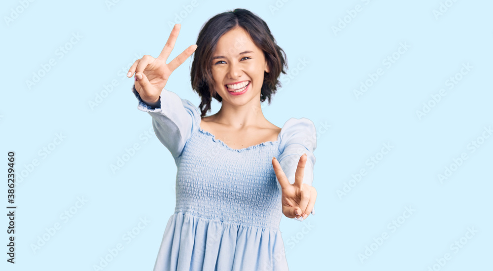 Young beautiful girl wearing casual clothes smiling with tongue out showing fingers of both hands doing victory sign. number two. Young beautiful girl wearing casual clothes smiling with tongue out showing fingers of both hands doing victory sign. number two.