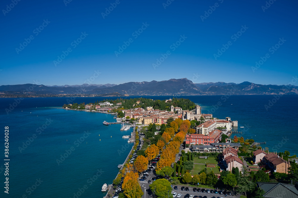 Top view of the town of Sirmione, Italy. Autumn in Italy on Lake Garda, Sirmione peninsula. Trees in the autumn season. Lake Garda, a tourist destination in northern Italy.