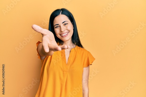 Beautiful young woman wearing casual clothes smiling friendly offering handshake as greeting and welcoming. successful business. © Krakenimages.com