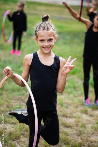 Obraz na płótnie Girl gymnast training with hoop and smiling on sports playground w salonie