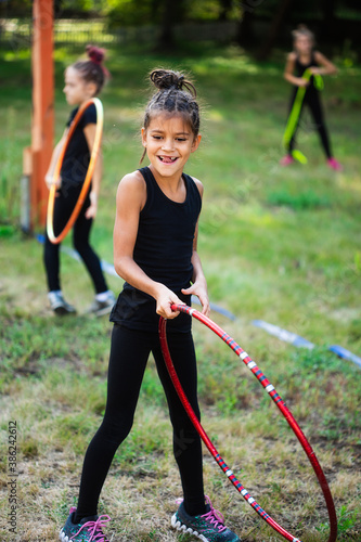 Girl gymnast training with hoop and smiling on sports playground
