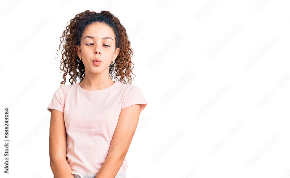 Beautiful kid girl with curly hair wearing casual clothes making fish face with lips, crazy and comical gesture. funny expression. Beautiful kid girl with curly hair wearing casual clothes making fish face with lips, crazy and comical gesture. funny expression.