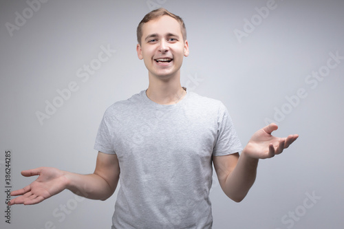 Studio portrait concept of a smiling young man talking on a white background. He stands directly in front of the camera in different poses with different emotions.