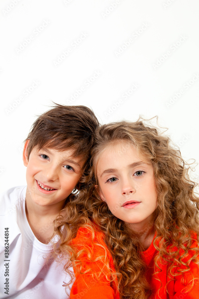 curly haired girl in an orange long sleeve t-shirt sits next to her friend in a white t-shirt curly haired girl in an orange long sleeve t-shirt sits next to her friend in a white t-shirt