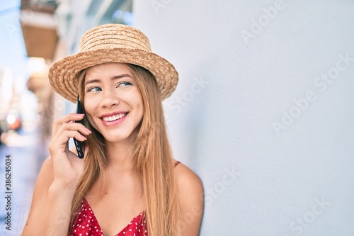 Young caucasian tourist girl smiling happy talking smartphone leaning on the wall.