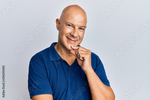 Middle age bald man wearing casual clothes smiling looking confident at the camera with crossed arms and hand on chin. thinking positive.