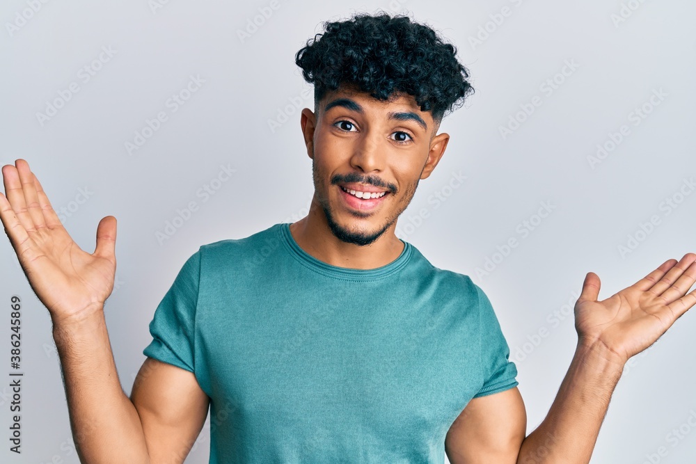 Young arab handsome man wearing casual clothes celebrating victory with happy smile and winner expression with raised hands Young arab handsome man wearing casual clothes celebrating victory with happy smile and winner expression with raised hands