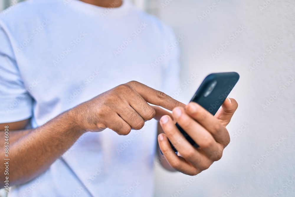 Young arab man smiling happy using smartphone leaning on the wall. Young arab man smiling happy using smartphone leaning on the wall.