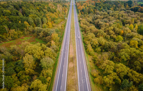 Aerial view of autumn colors in the forest with highway crossing it