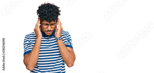 Young arab man wearing casual clothes and glasses with hand on head for pain in head because stress. suffering migraine.
