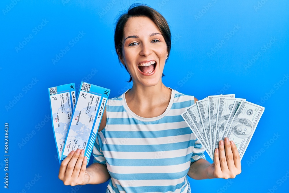 Young brunette woman with short hair holding boarding pass and dollars smiling and laughing hard out loud because funny crazy joke.