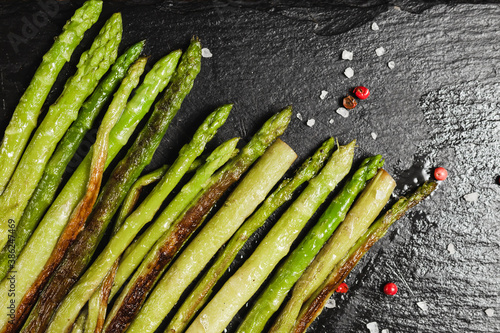 asparagus stalks on a black mica Board with pepper peas and salt crystals