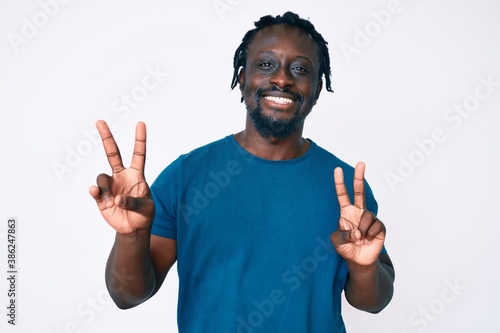 Young african american man with braids wearing casual clothes smiling looking to the camera showing fingers doing victory sign. number two.