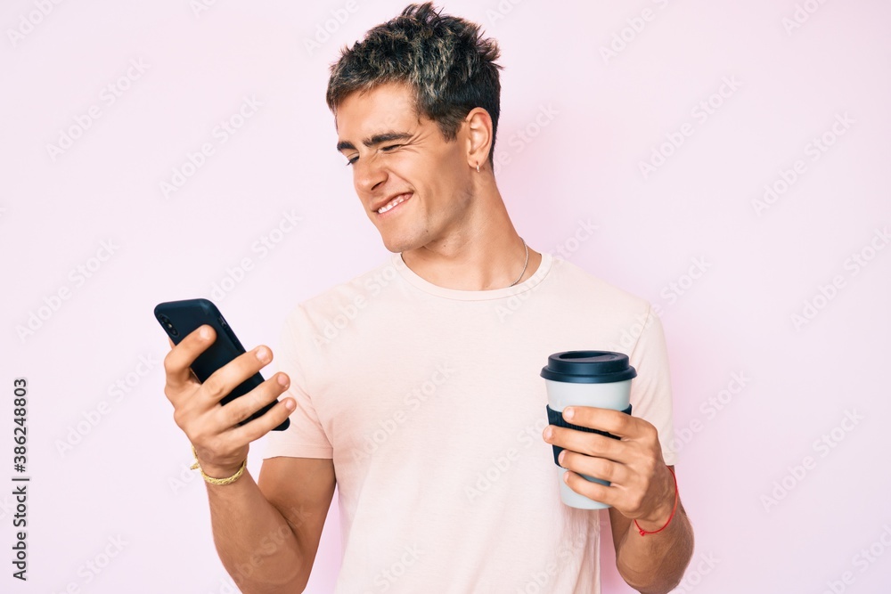 Young handsome man using smartphone holding take away coffee winking looking at the camera with sexy expression, cheerful and happy face. Young handsome man using smartphone holding take away coffee winking looking at the camera with sexy expression, cheerful and happy face.