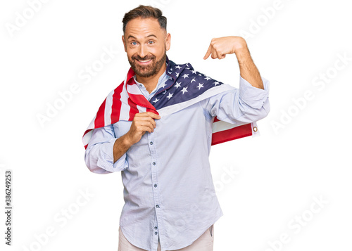 Handsome middle age man holding united states flag smiling happy pointing with hand and finger