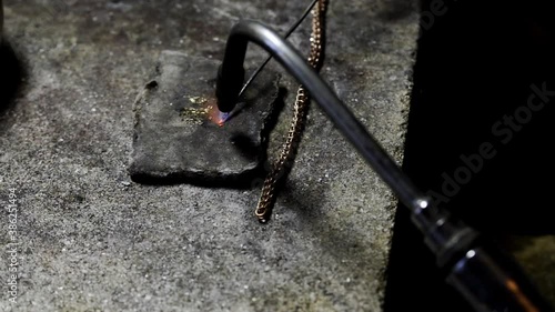 soldering gold chain. the jeweler at the work table soldered the piece. close-up