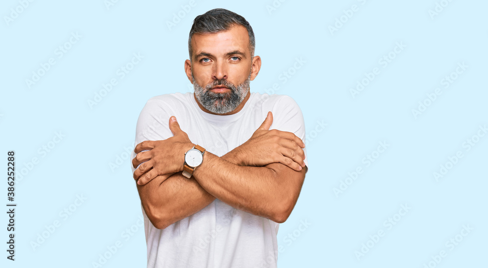 Middle age handsome man wearing casual white tshirt shaking and freezing for winter cold with sad and shock expression on face Middle age handsome man wearing casual white tshirt shaking and freezing for winter cold with sad and shock expression on face